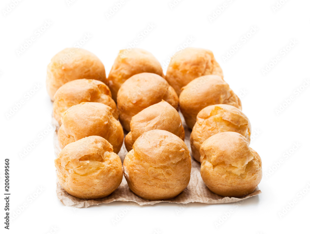 Homemade profiteroles on baking paper isolated on white Homemade profiteroles on baking paper isolated on white