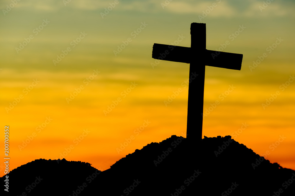 Concept conceptual yellow cross religion symbol silhouette in nature over sunset or sunrise sky Concept conceptual yellow cross religion symbol silhouette in nature over sunset or sunrise sky