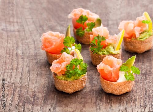 Croustades  crispy pastry cases filled with salted salmon and avocado on wooden table photo