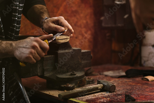 Man works in carpentry workshop. He cuts off excess wood with knife with an ax. photo