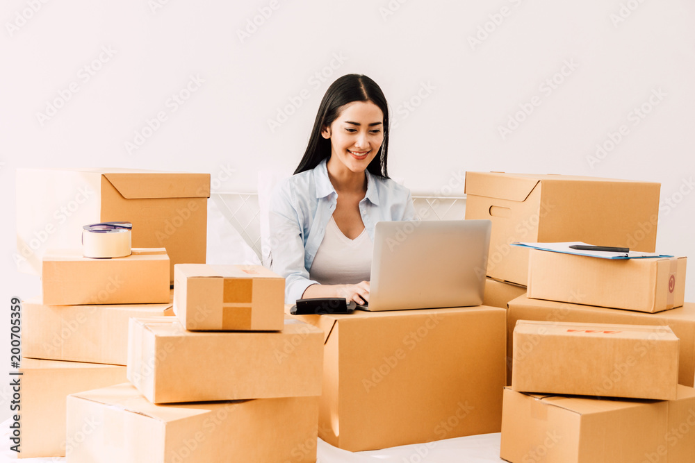 Young woman working and use laptop computer with cardboard box on bed at home - Business online and delivery concept Young woman working and use laptop computer with cardboard box on bed at home - Business online and delivery concept