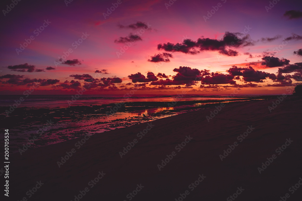 Bright colorful sunset or sunrise at ocean with clouds in Bali
