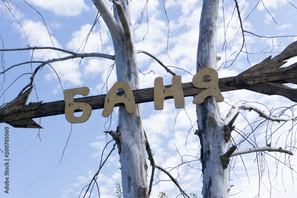 Metal artwork spelling out the word bath on a knotty pine wall. Stock Photo | Adobe Stock