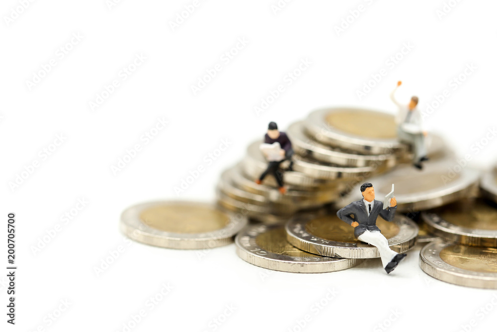 Naklejka premium Miniature people: businessmen sitting on coins and reading newspaper, book using as background saving planing, Money, Financial, Business