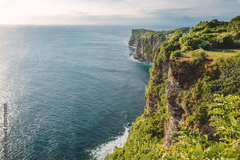 Ocean and cliff with rocks and trees in Bali