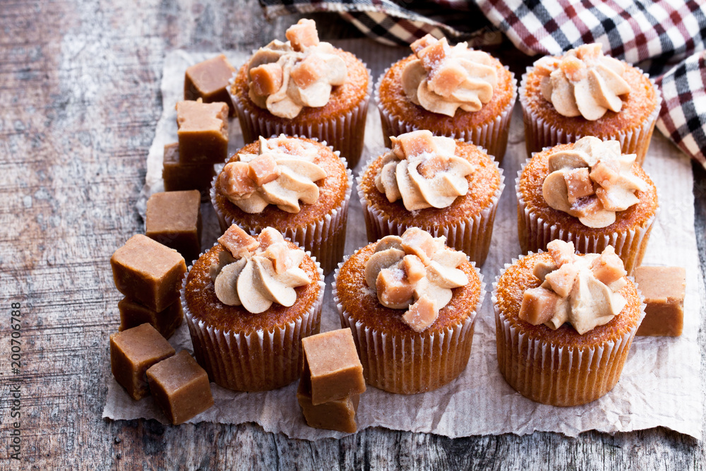 Toffee cupcakes with white cream on wooden table Toffee cupcakes with white cream on wooden table