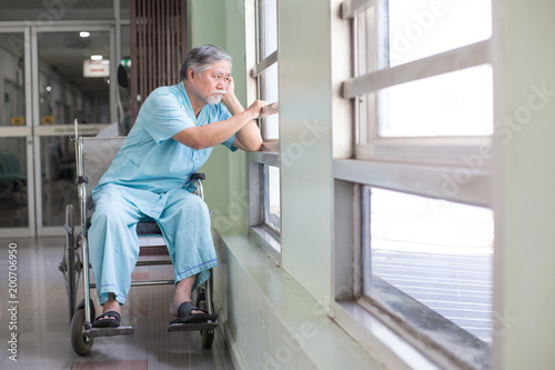 Asian old man sit on wheelchair looking out to other place. People with health care and medical concept.