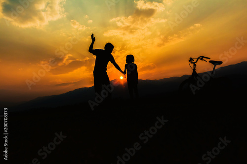 Man and little girl silhouettes on mountain at sunset,Child abuse and bullying in the family.