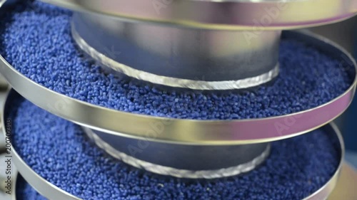 The blue round granules move up the vibrating screw conveyor.