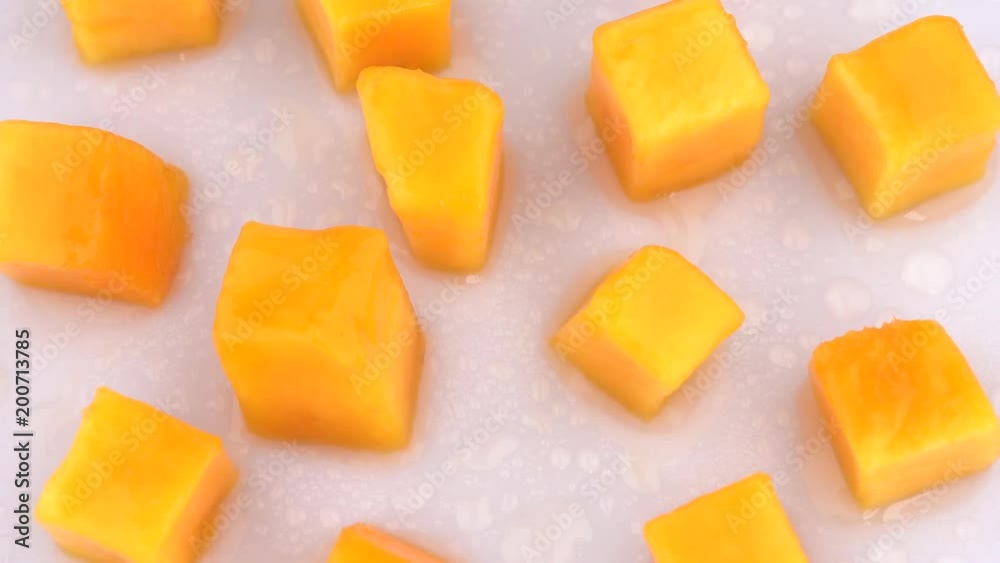 Juicy mango fruit slices rotating on turn table. Isolated on white background. Loopable. Close up macro. View from above/overhead. Juicy mango fruit slices rotating on turn table. Isolated on white background. Loopable. Close up macro. View from above/overhead.