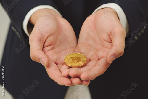 Young man hand holding up golden bitcoin in two hand. Close up of bitcoin in open hand isolated on white background.