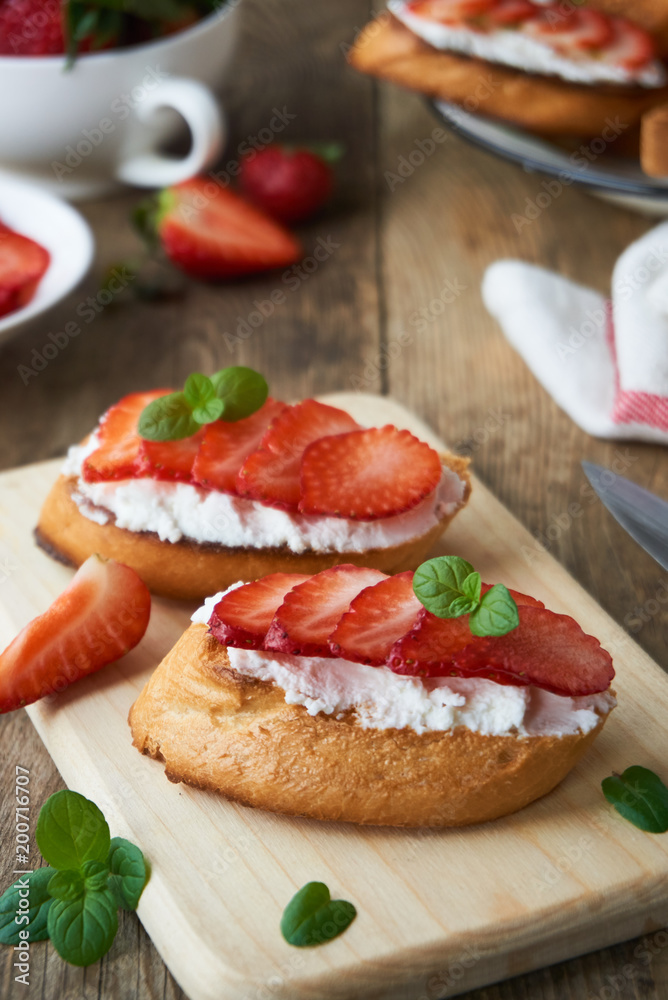 Bruschetta with ricotta cheese and strawberries on a wooden board        