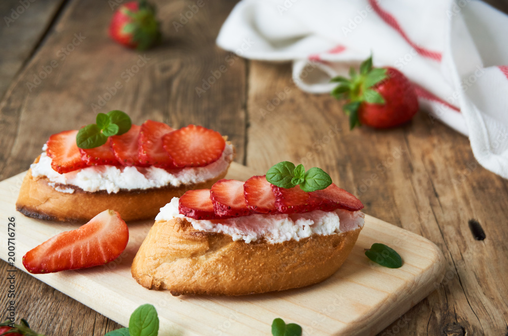 Bruschetta with ricotta cheese and strawberries on a wooden board        