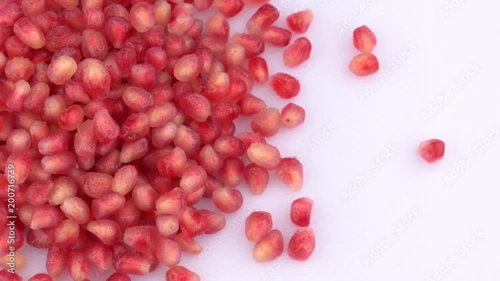 Pomegranate seeds in drops of water rotating on turn table. Isolated on white background. Loopable. Close up macro. View from above/overhead. Pomegranate seeds in drops of water rotating on turn table. Isolated on white background. Loopable. Close up macro. View from above/overhead.