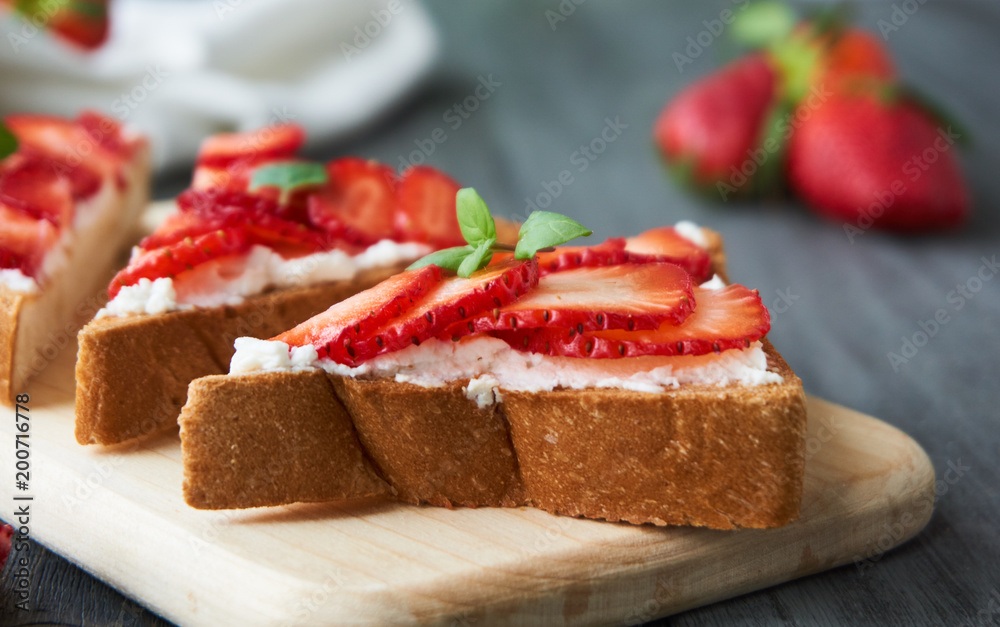 Toast with ricotta cheese and strawberries on a wooden board Toast with ricotta cheese and strawberries on a wooden board