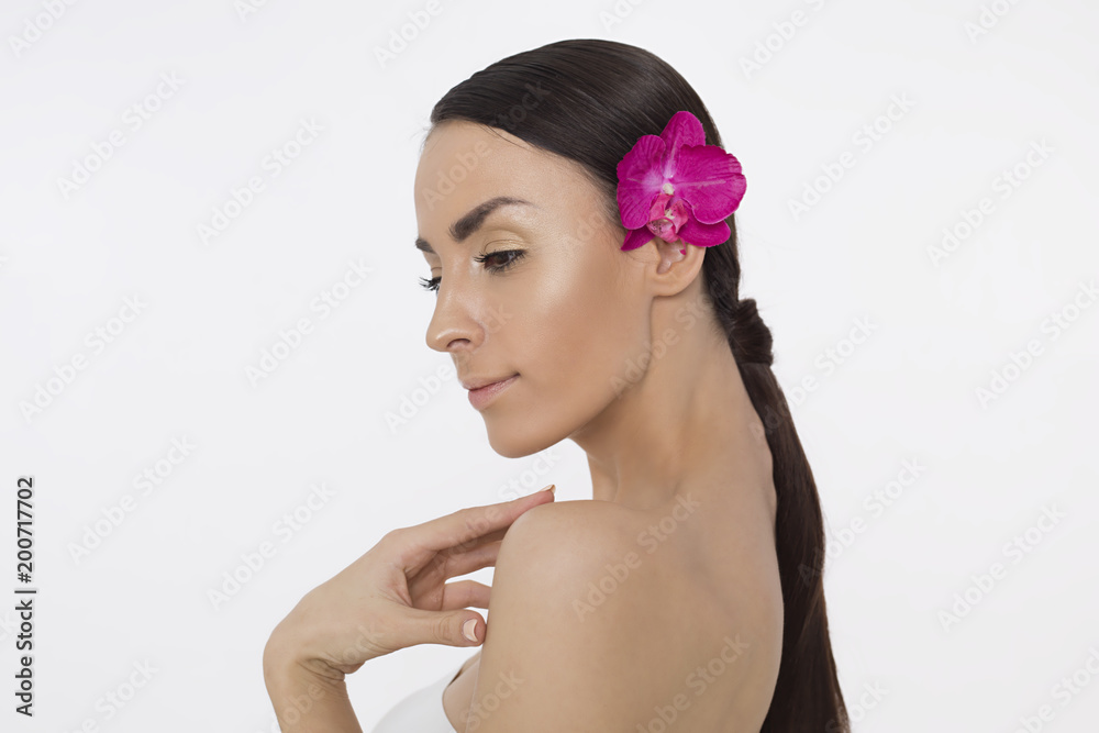Naklejka premium Beautiful young smiling woman with clean skin and flower on head posing on white background. Beauty and spa. Face and body care. Women's health. Cosmetology.