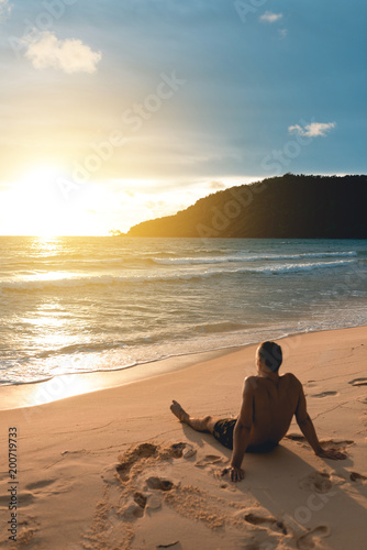 Young handsome man siting at the lazy beach and enjoying the sunset. Koh Rong Samloem island. Cambodia, Asia © stockcrafter