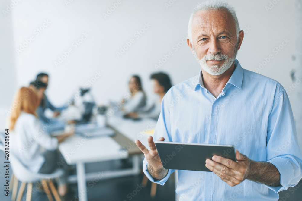 Senior businessman standing with digital tablet in his hand Senior businessman standing with digital tablet in his hand