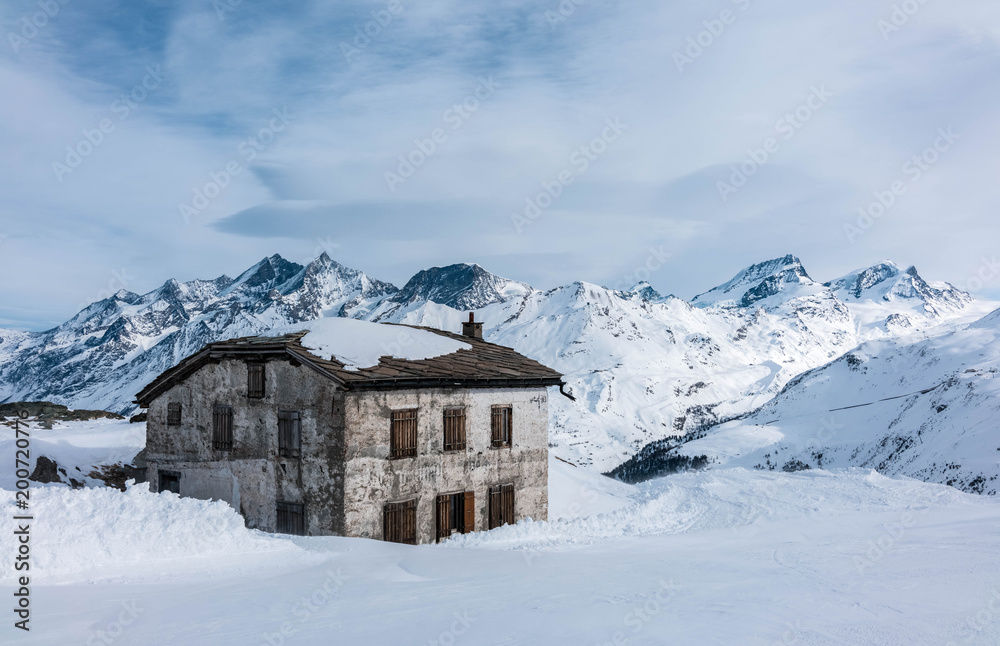 House on a mountainside against a backdrop of mountain peaks. Zermatt Ski Resort Switzerland