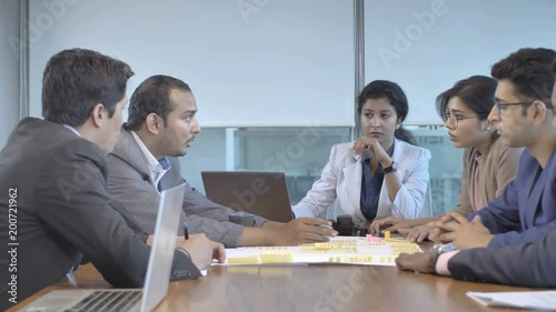 A young diverse mixed gender Indian team members brainstorming on a business development plan. Male/ men and female/ women office colleagues talking among the multi ethnic team in a conference room