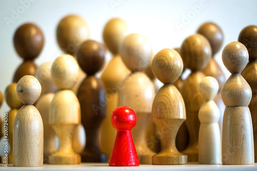 red large isolated wooden figure in the foreground, many blurred big figures in the background, systemic board, family therapy