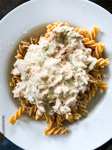 Vollkornnudeln mit Lachs-Sahne-Sauce mitn geriebenem Parmesan angerichtet auf einem weißen Teller photo