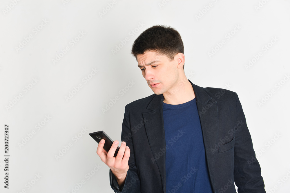 man, student or freelancer in a jacket, emotionally posing with a phone man, student or freelancer in a jacket, emotionally posing with a phone