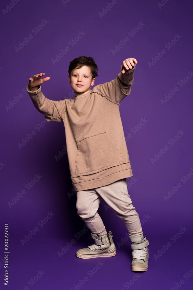 Style is more about being yourself! Young smiling boy wearing beige fleece jacket grooving and having wonderful time during his holidays.