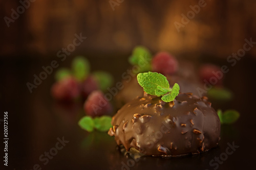 Chocolate cakes witn nuts, mint and ruspberry on dark background, bird milk in chocolate glaze photo
