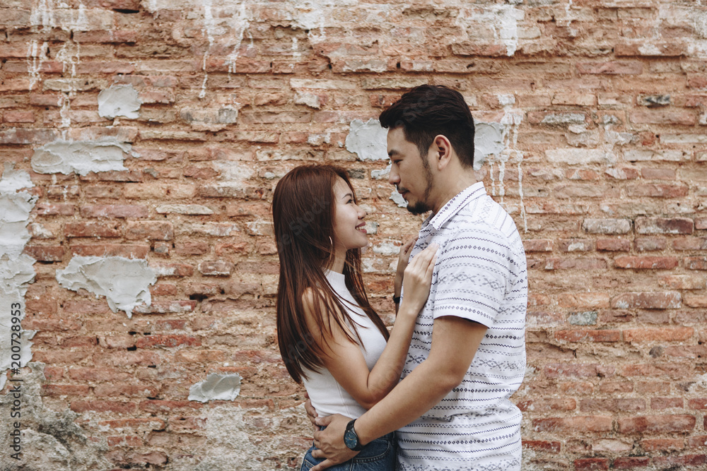 Lovely asian couple by a brick wall