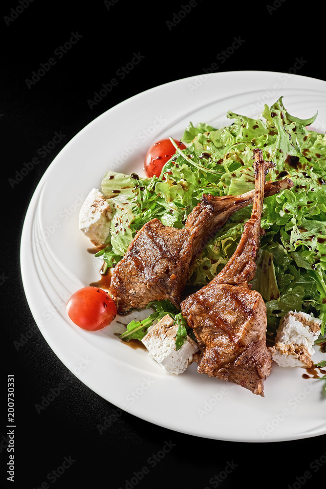 Grilled lamb ribs with onion, salad and sliced tomato