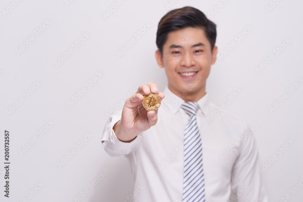 A young business man model holds a bitcoin gold coin A young business man model holds a bitcoin gold coin