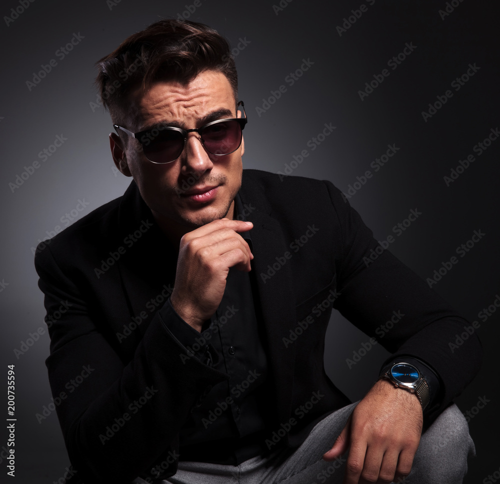 Obraz premium young fashion man with sunglasses sitting and thinking