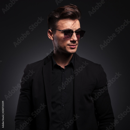 happy handsome fashion man with sunglasses looks to side