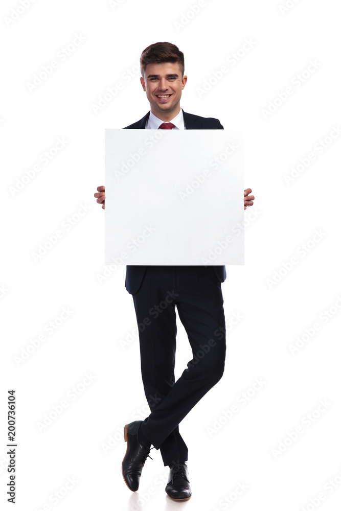 smiling businessman standing with legs crossed holds white empty board smiling businessman standing with legs crossed holds white empty board