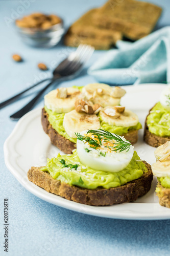 Toasted bread with avocado, eggs, banana and nuts. Selective focus, space for text, close up.