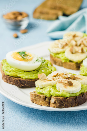 Toasts with avocado, eggs, banana and nuts. Selective focus, space for text, close up.