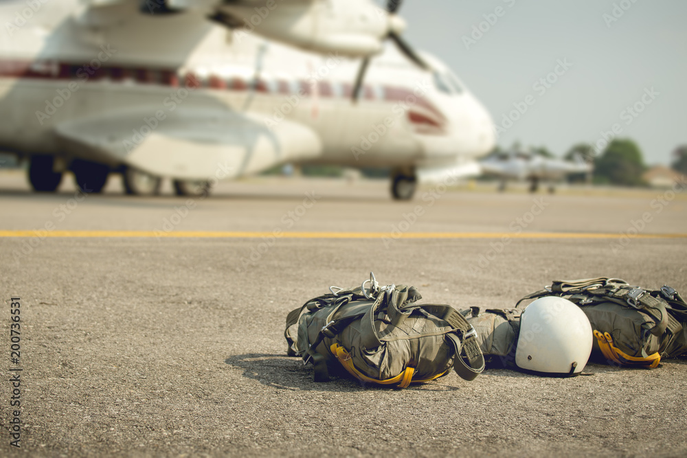 Parachute with equipment for paratroop on ground and military transport aircraft background in cinematic tone