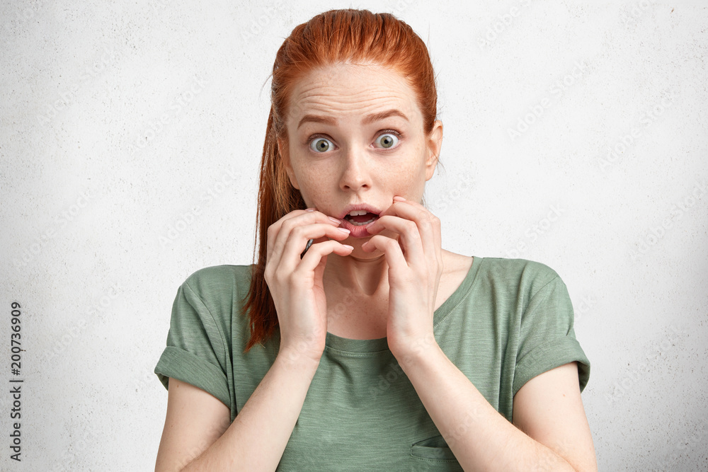 Portrait of scared beautiful red haired young woman looks with