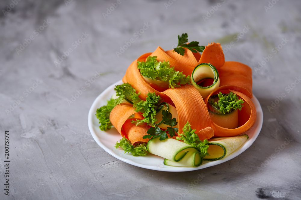 Artistically served vegetable salad with carrot, cucumber, letucce over white background, selective focus