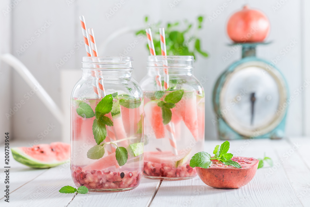 Water in jar with pomegranate and watermelon on white table Water in jar with pomegranate and watermelon on white table