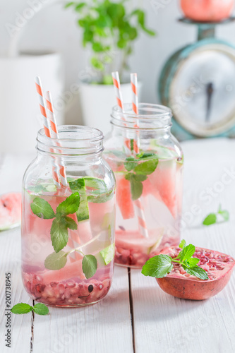 Water in jar with watermelon, pomegranate and mint leaves