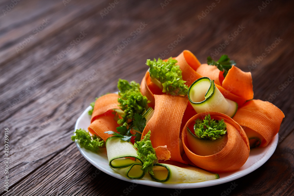 Artistically served vegetable salad with carrot, cucumber, letucce over wooden background, selective focus Artistically served vegetable salad with carrot, cucumber, letucce over wooden background, selective focus
