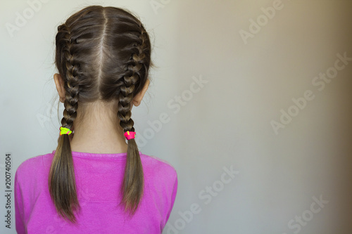 Close up rear- vew portrait of a cute little girl with funny pigtails on white background. Fashion and happy childhood. photo
