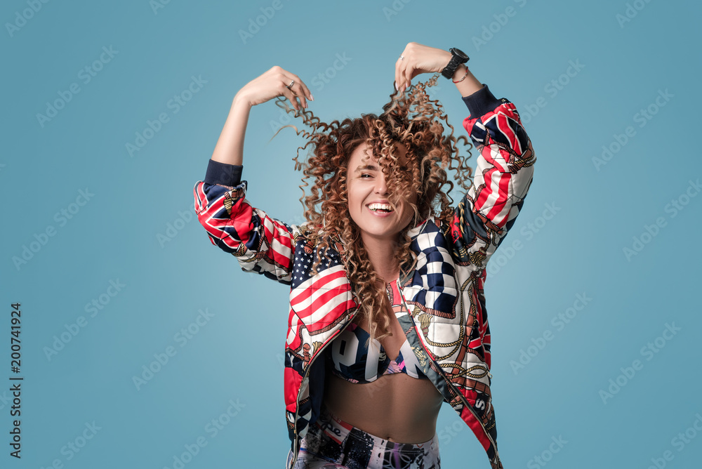 Portrait of a young girl with curly hair with eyes surprised. She holds his hair with his hands and laughs with joy, looks at the camera Portrait of a young girl with curly hair with eyes surprised. She holds his hair with his hands and laughs with joy, looks at the camera
