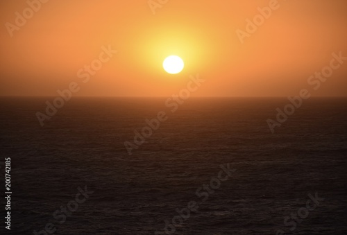 Bright orange sunset lowering peacefully over the ocean