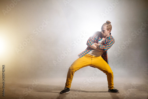 young male with crossed arms and legs apart is waiting for his solo in dance. presenting his dance style photo