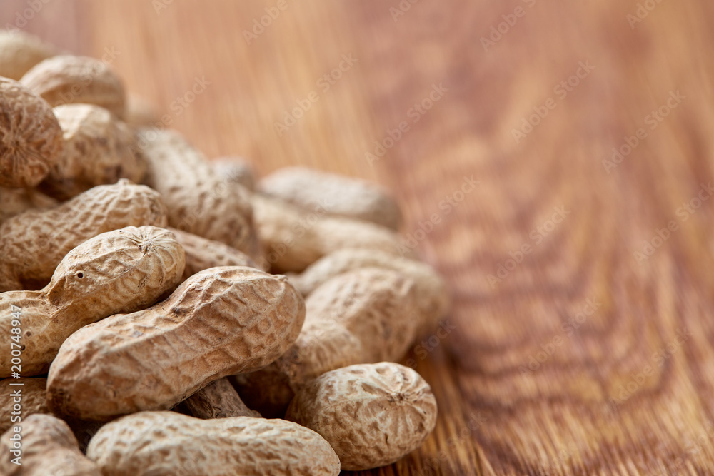 Unpeeled peanuts on a wooden background, top view, selective focus, shallow depth of field. Unpeeled peanuts on a wooden background, top view, selective focus, shallow depth of field.