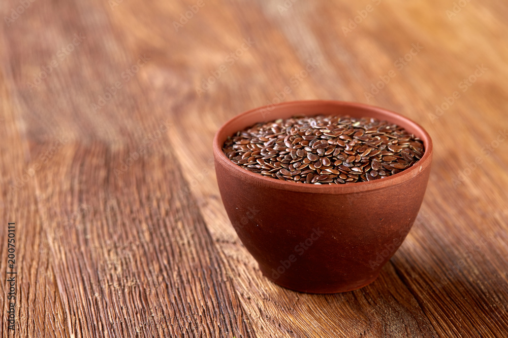 Flax seeds in wooden bowl on rustic wooden background, top view, selective focus Flax seeds in wooden bowl on rustic wooden background, top view, selective focus