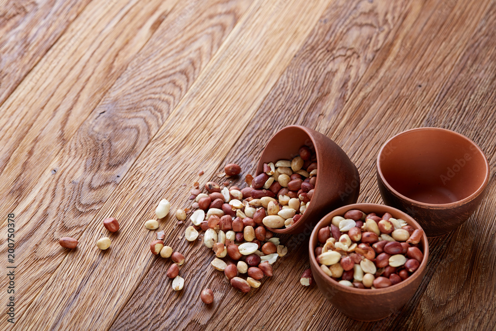 Two ceramic bowls with raw peanuts mix isolated over rustic wooden backround, top view, close-up. Two ceramic bowls with raw peanuts mix isolated over rustic wooden backround, top view, close-up.